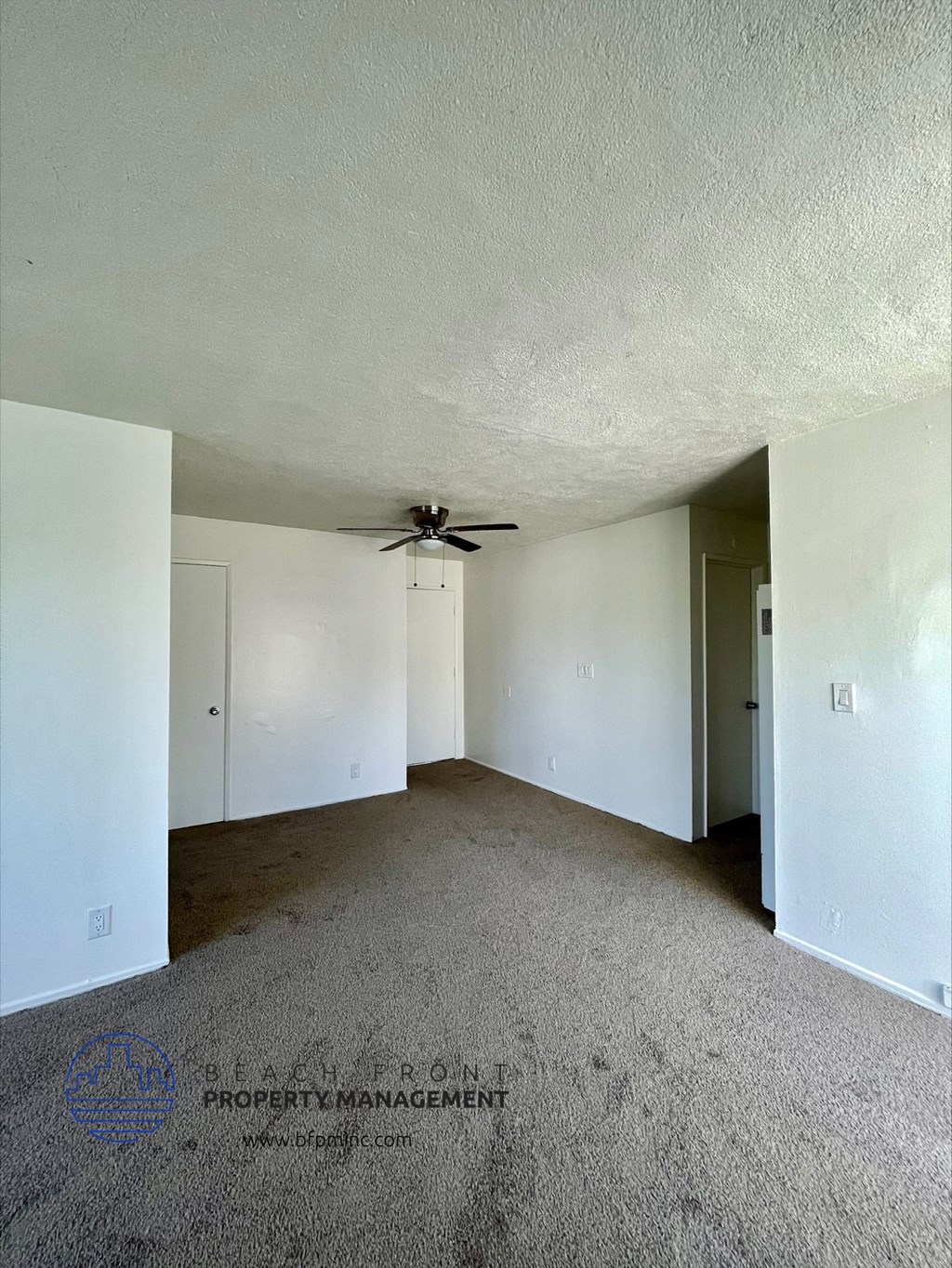 an empty living room with a ceiling fan